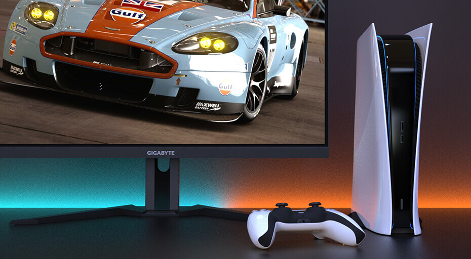 A playstation and a controller are next to a Gigabyte monitor